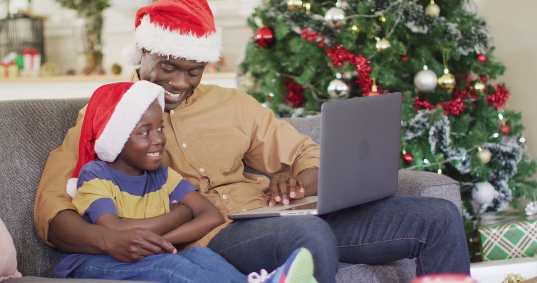 Father and Son Using Laptop on Christmas Day with Santa Hats - Free Images, Stock Photos and Pictures on Pikwizard.com