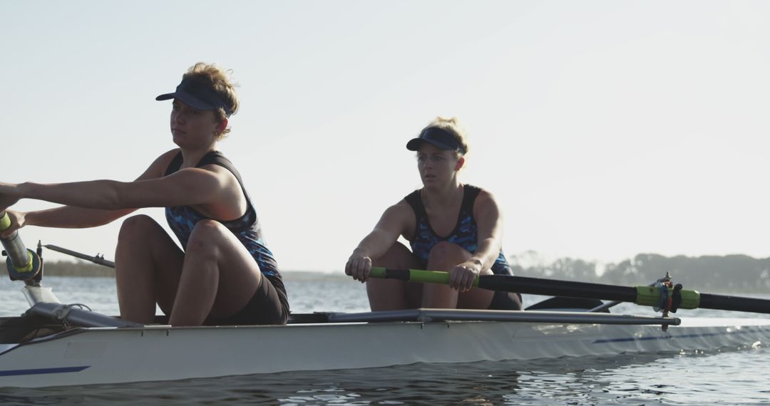 Two female rowers training on calm lake in early morning - Free Images, Stock Photos and Pictures on Pikwizard.com