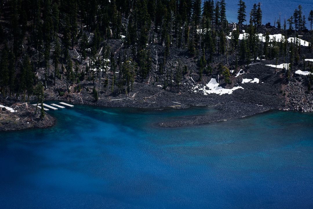 Pristine Blue Lake with Forested Shoreline and Snow Patches - Free Images, Stock Photos and Pictures on Pikwizard.com