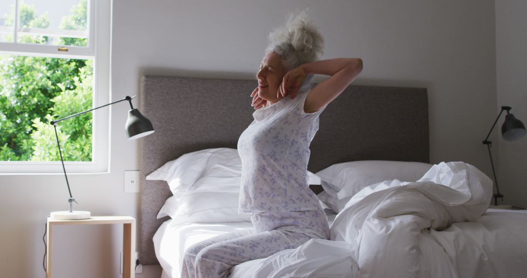 Elderly Woman Stretching on Bed in Morning Light - Free Images, Stock Photos and Pictures on Pikwizard.com