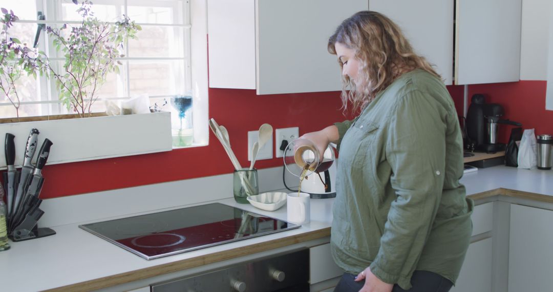 Woman Preparing Morning Coffee in Modern Kitchen with Red Accents - Free Images, Stock Photos and Pictures on Pikwizard.com