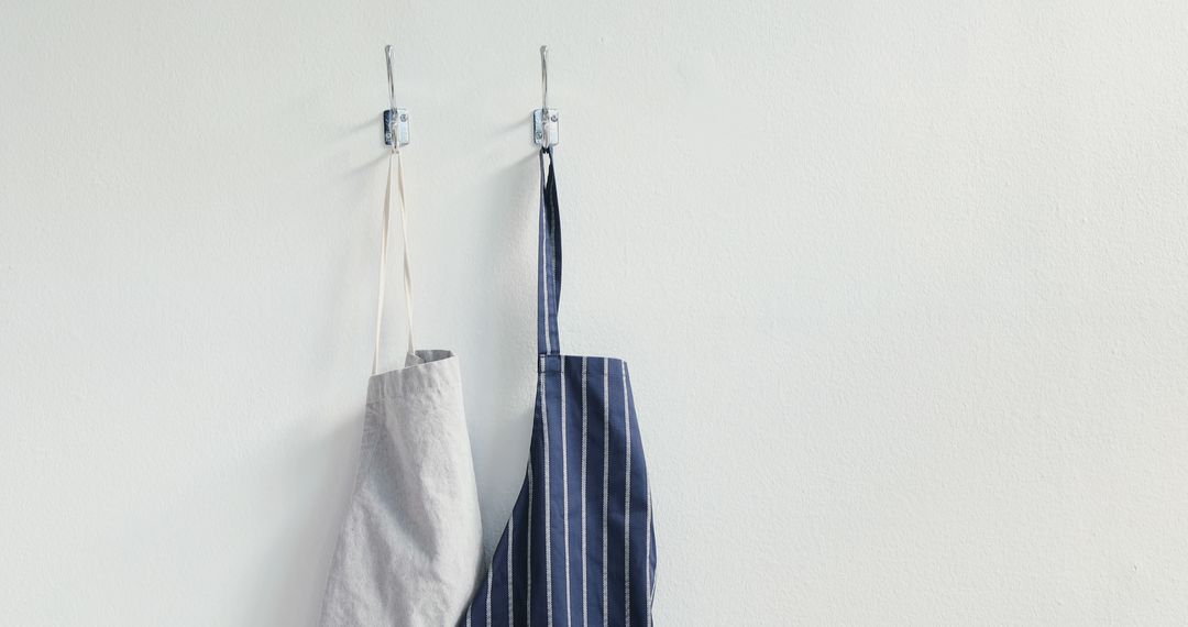 Two Aprons Hanging on Wall with Simple Hooks - Free Images, Stock Photos and Pictures on Pikwizard.com