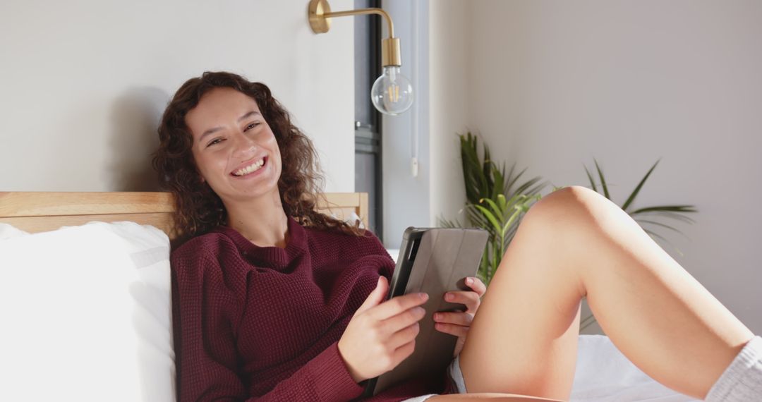 Woman Relaxing on Bed with Tablet in Cozy Bedroom Setup