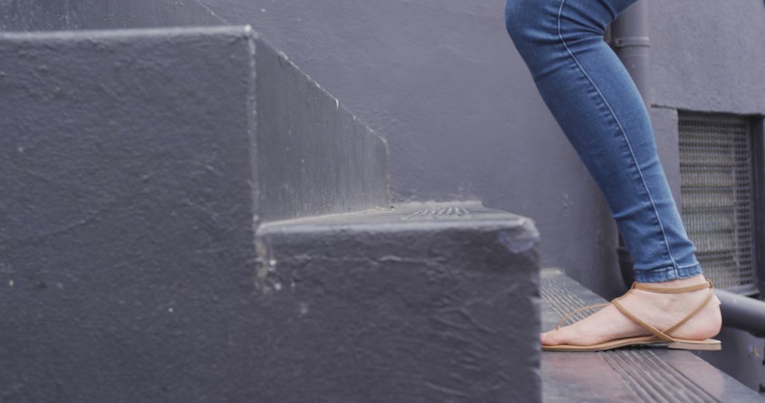 A woman in jeans and sandals ascends city stairs in daylight. - Free Images, Stock Photos and Pictures on Pikwizard.com