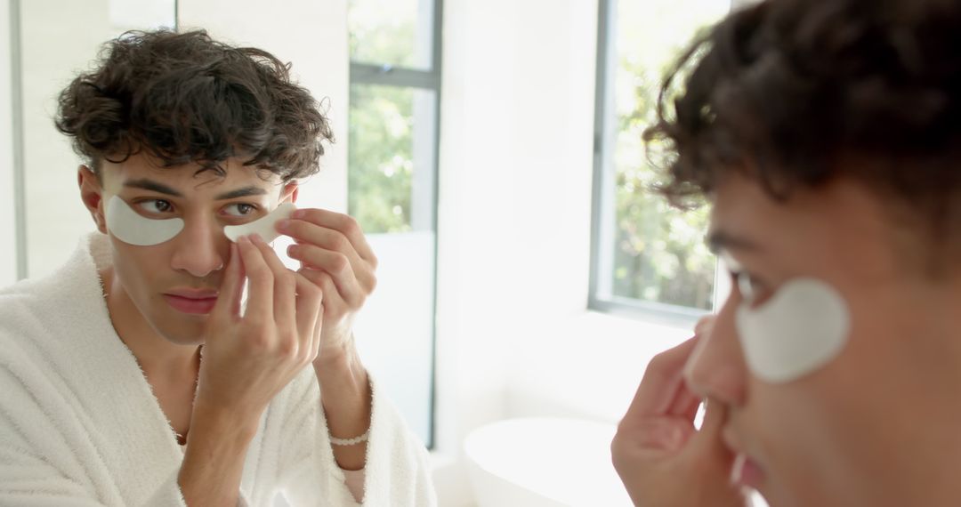 Man Applying Under-Eye Gel Patches in Bathroom for Skincare and Self-Care
