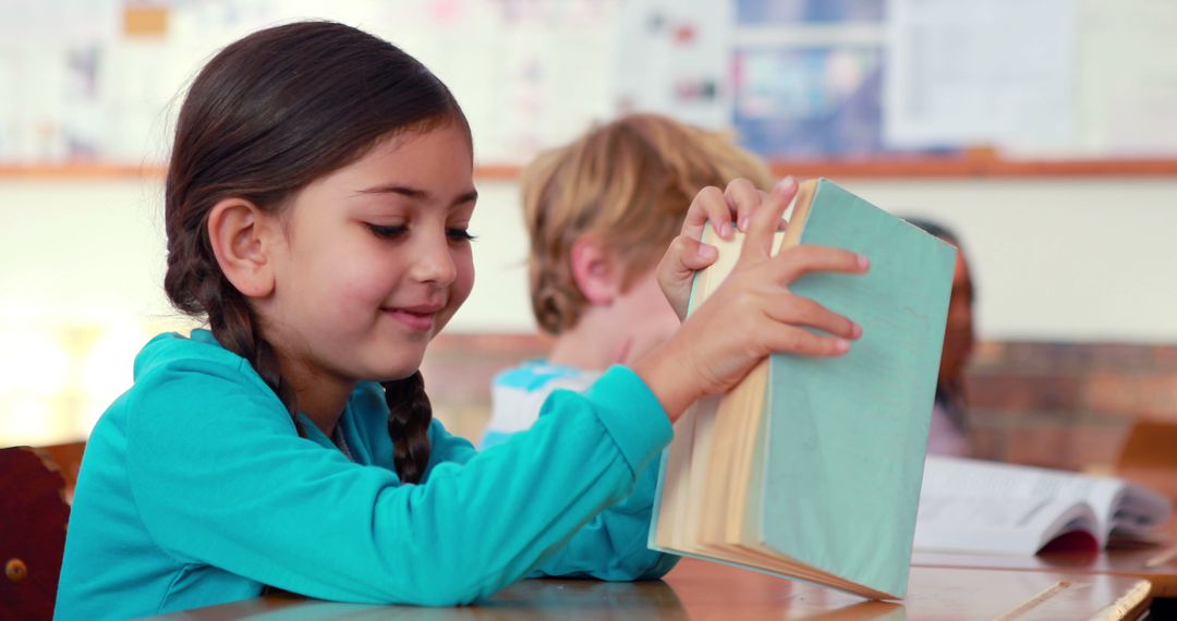 Smiling Elementary School Girl Reading Book in Classroom - Free Images, Stock Photos and Pictures on Pikwizard.com