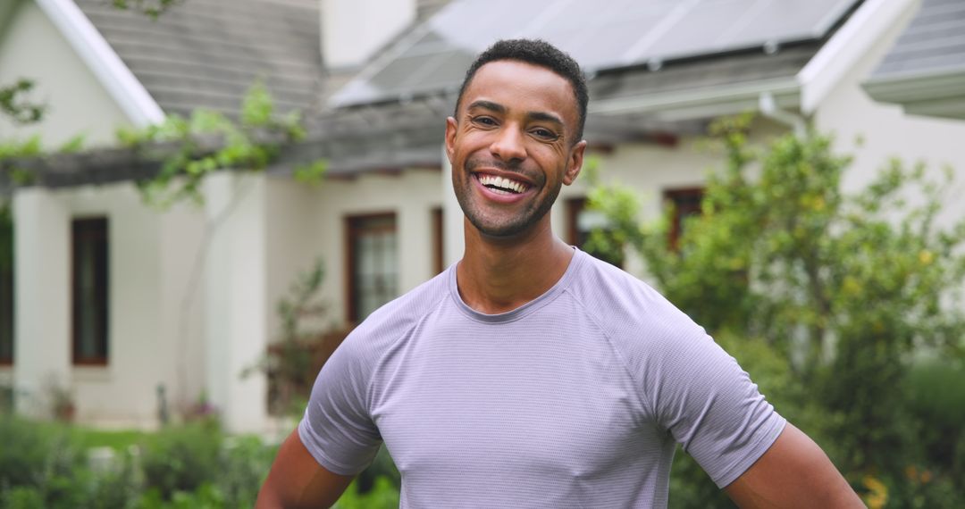 Smiling Man in Eco-Friendly Home Yard with Solar Panels