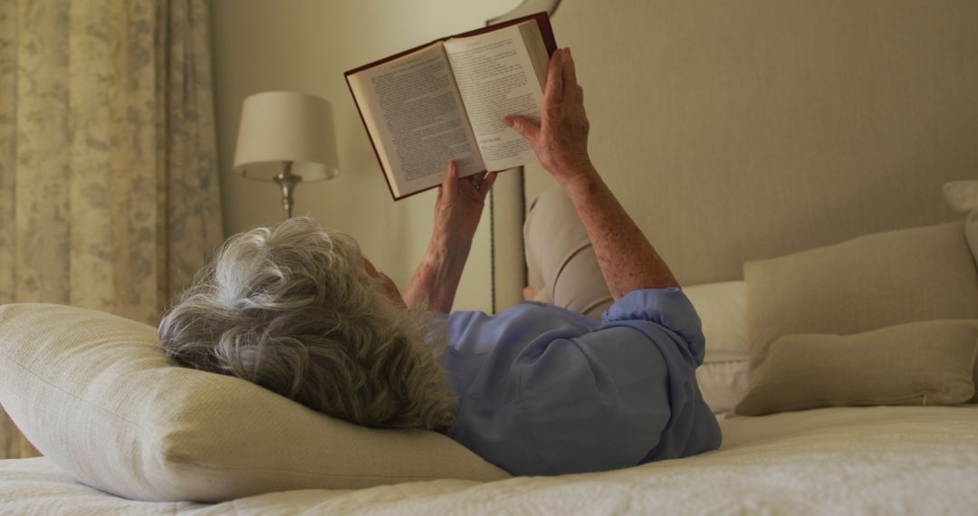 Caucasian senior woman reading a book while lying on the bed at home - Free Images, Stock Photos and Pictures on Pikwizard.com