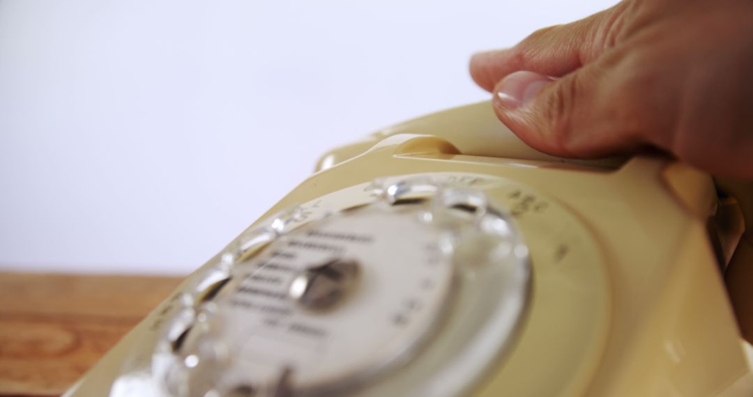 A person's hand is seen dialing on a vintage rotary telephone, with copy space - Free Images, Stock Photos and Pictures on Pikwizard.com