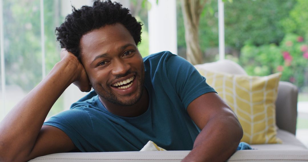 Smiling Young Man Relaxing on Couch in Bright Living Room