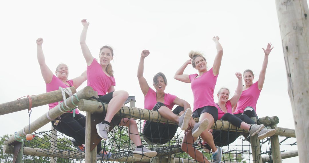 Happy caucasian female friends in pink t shirts celebrating on climbing frame at bootcamp - Free Images, Stock Photos and Pictures on Pikwizard.com