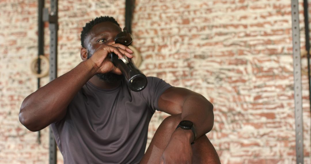 Man in Gym Drinking from Water Bottle Wearing Smartwatch on Break