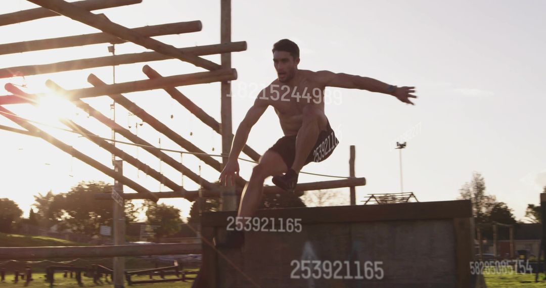 Shirtless Man Jumping Over Obstacle at Sunset in Park