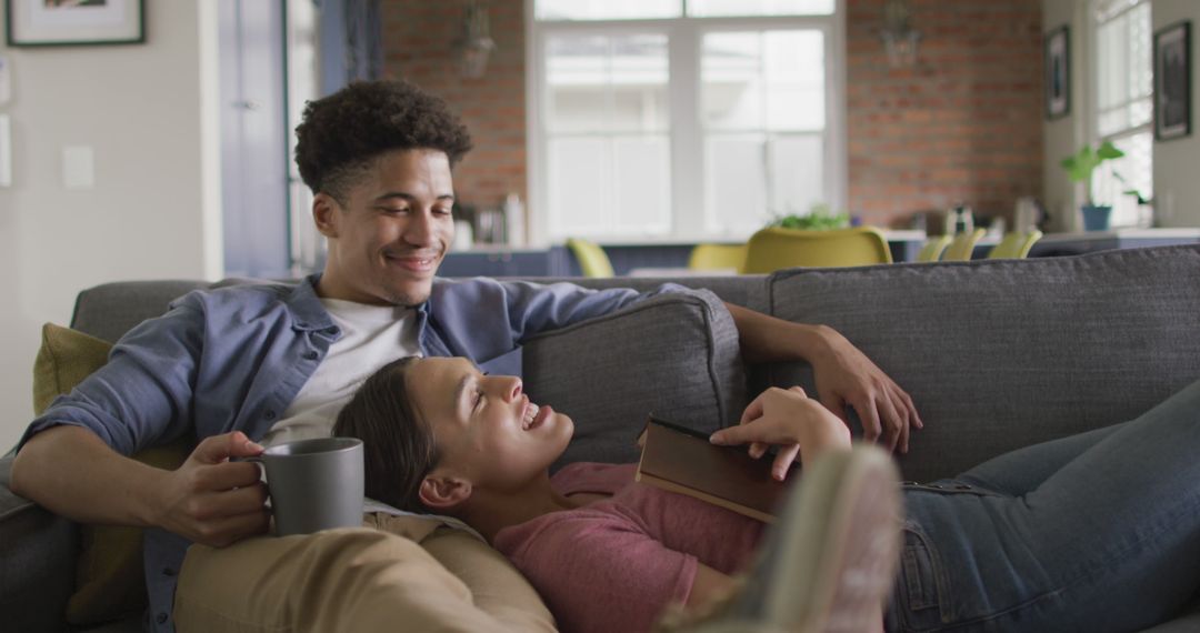 Biracial Couple Relaxing on Sofa with Coffee at Home
