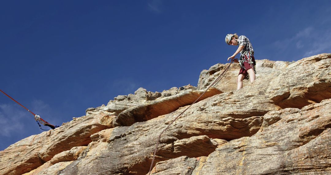 Rock climber abseiling on rocky cliff under sunny sky - Free Images, Stock Photos and Pictures on Pikwizard.com