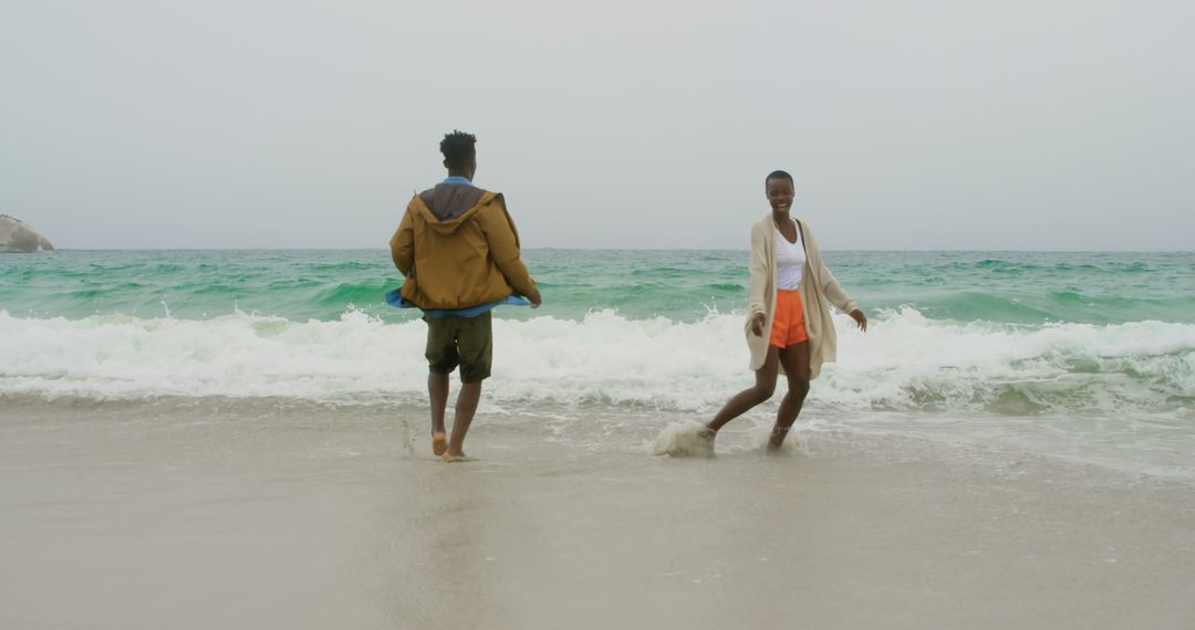 Joyful Couple Embracing Beach Waves in Relaxed Atmosphere