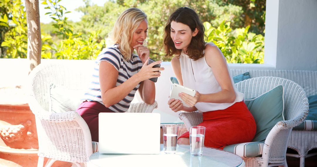 Two Women Networking with Smartphone and Tablet in Outdoor Patio - Free Images, Stock Photos and Pictures on Pikwizard.com