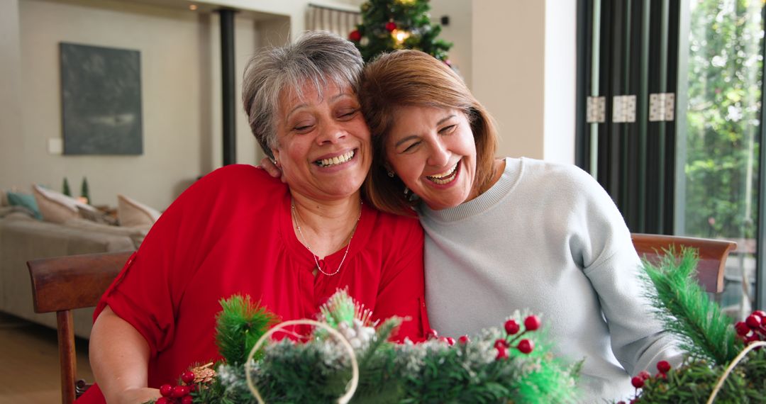 Two Women Smiling Together at Home Dining Table during Holidays