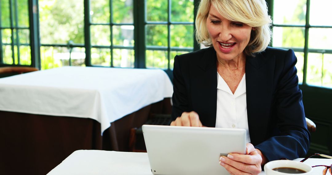 Smiling Businesswoman Using Tablet in Bright Restaurant - Free Images, Stock Photos and Pictures on Pikwizard.com