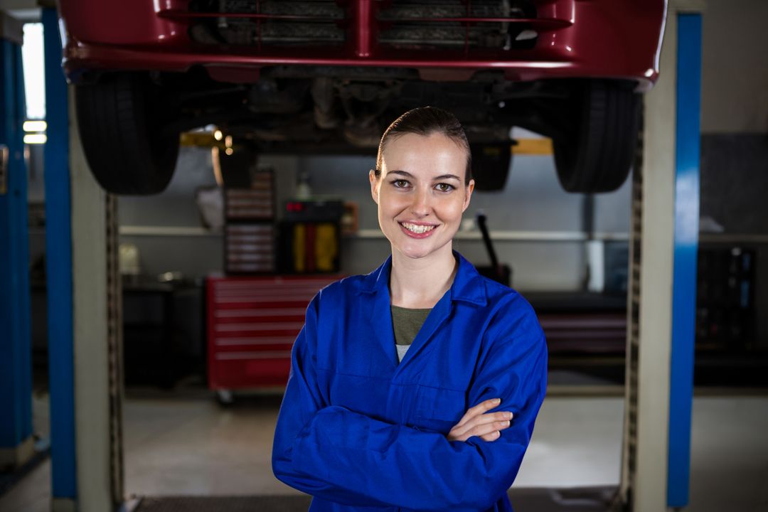 Female Mechanic with Crossed Arms Under Car on Lift in Workshop