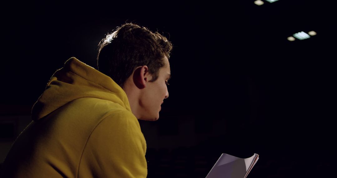 Young Man Reading a Book Alone in Dimly Lit Room - Free Images, Stock Photos and Pictures on Pikwizard.com