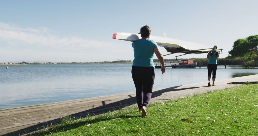 Two Mature Women Carrying Rowing Boat by Lakeside - Free Images, Stock Photos and Pictures on Pikwizard.com