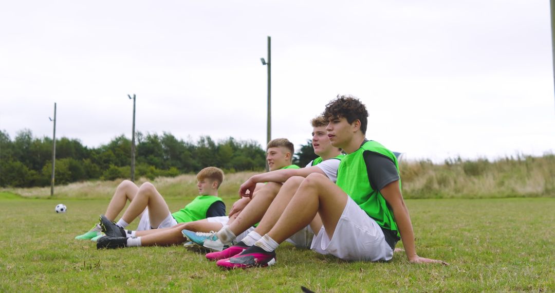 Teenage Soccer Team Resting on Field in Green Training Vests