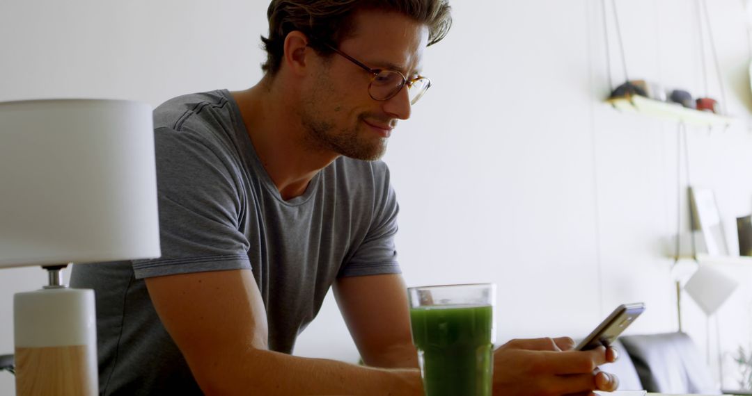 Casual Man Texting While Enjoying Green Smoothie at Home - Free Images, Stock Photos and Pictures on Pikwizard.com