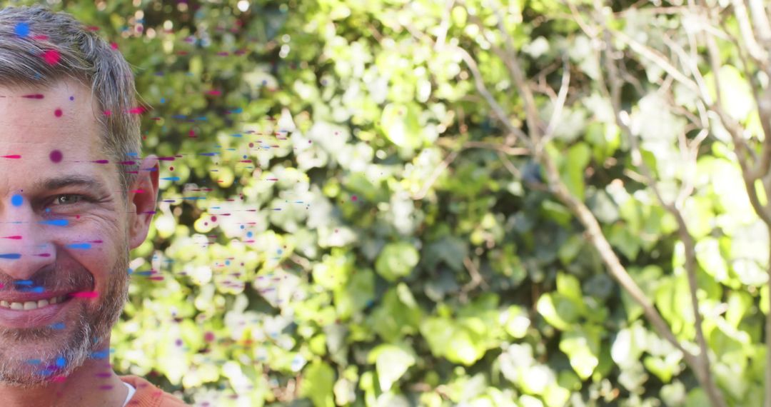 Smiling mature man posing in garden with colorful paint splashes and lush ivy backdrop