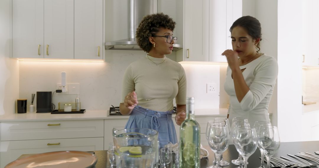 Two Women Preparing Tableware in Conversation in Modern Kitchen