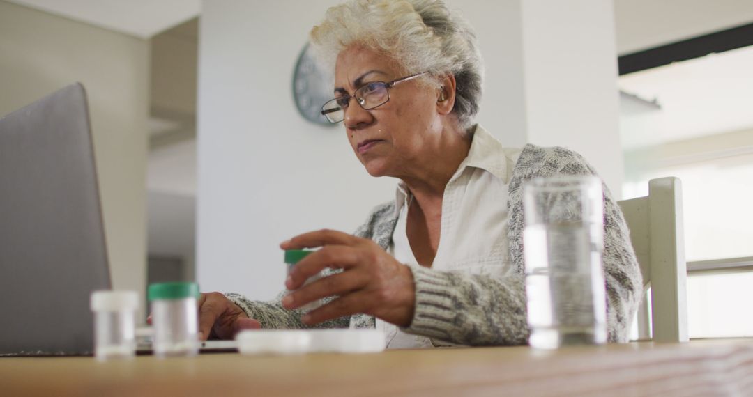 Senior Woman Managing Medications While Using Laptop at Home - Free Images, Stock Photos and Pictures on Pikwizard.com