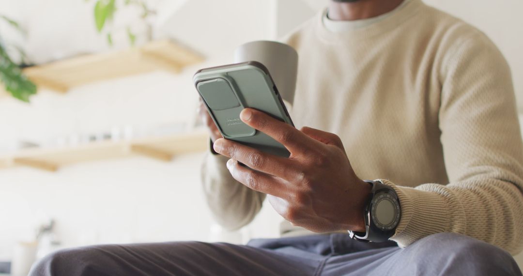 Man Holding Smartphone and Mug in Modern Home Interior - Free Images, Stock Photos and Pictures on Pikwizard.com