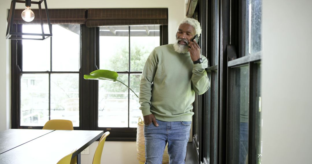 Senior Man Relaxing Indoors Using Smartphone with Natural Light