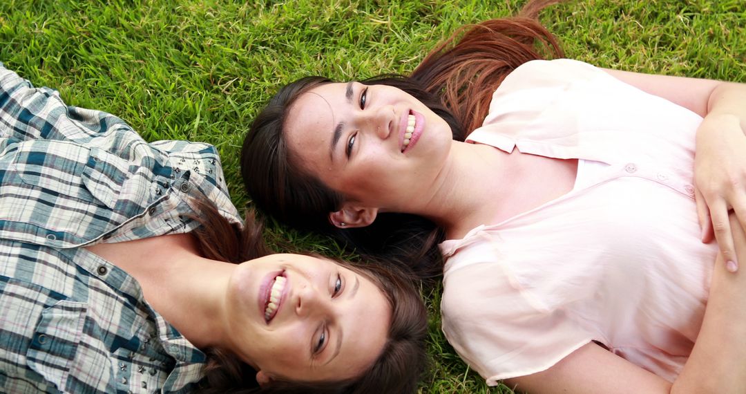 Two Young Women Lying on Grass, Smiling at Camera - Free Images, Stock Photos and Pictures on Pikwizard.com