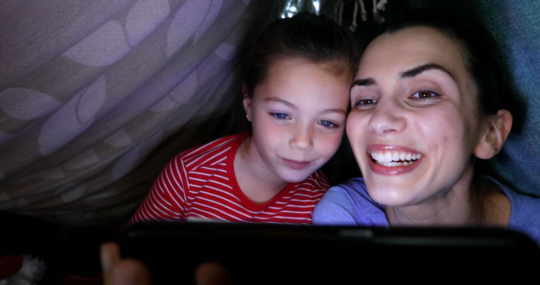 Mother and Daughter Smiling Inside Cozy Blanket Fort Admires Smartphone Screen - Free Images, Stock Photos and Pictures on Pikwizard.com