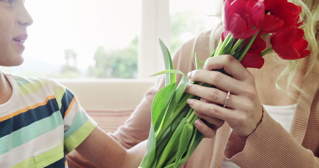 Child Giving Red Tulip Bouquet to Blond Woman Indoors - Free Images, Stock Photos and Pictures on Pikwizard.com