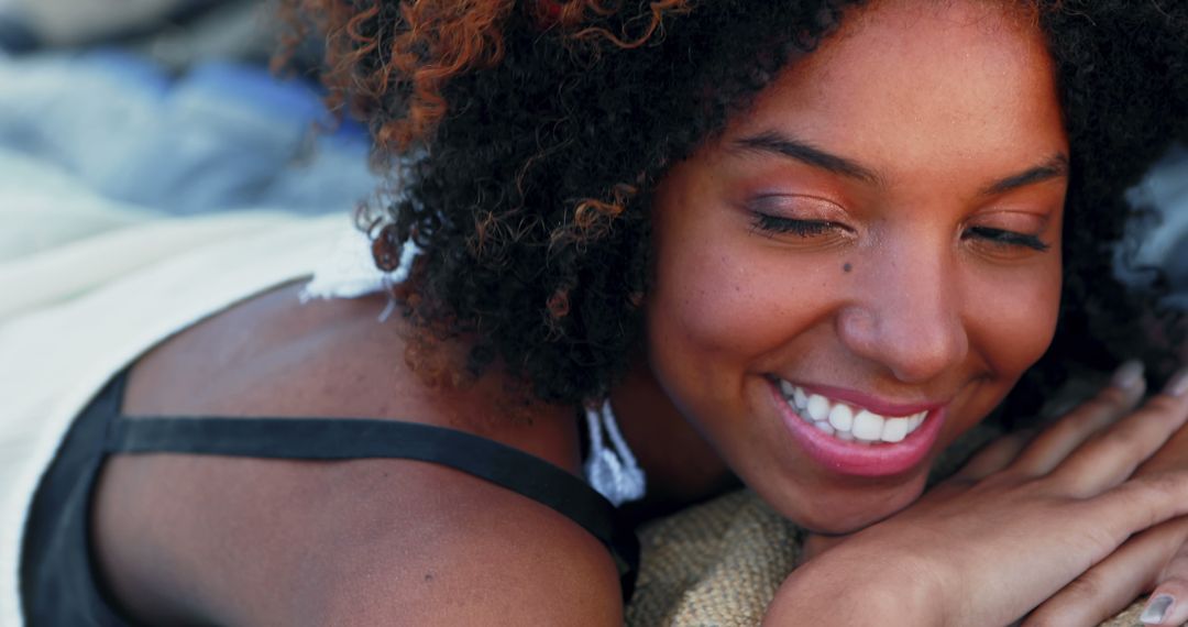 Young Woman Smiling While Lying Down with Curly Hair - Free Images, Stock Photos and Pictures on Pikwizard.com