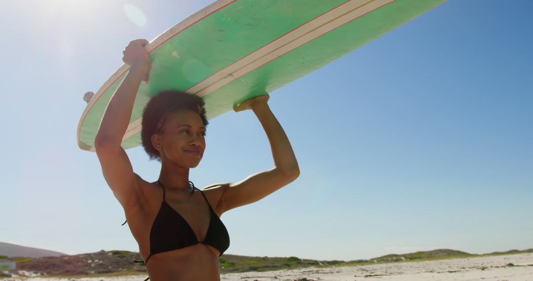 Young African American woman holds a surfboard on the beach, with copy space - Free Images, Stock Photos and Pictures on Pikwizard.com
