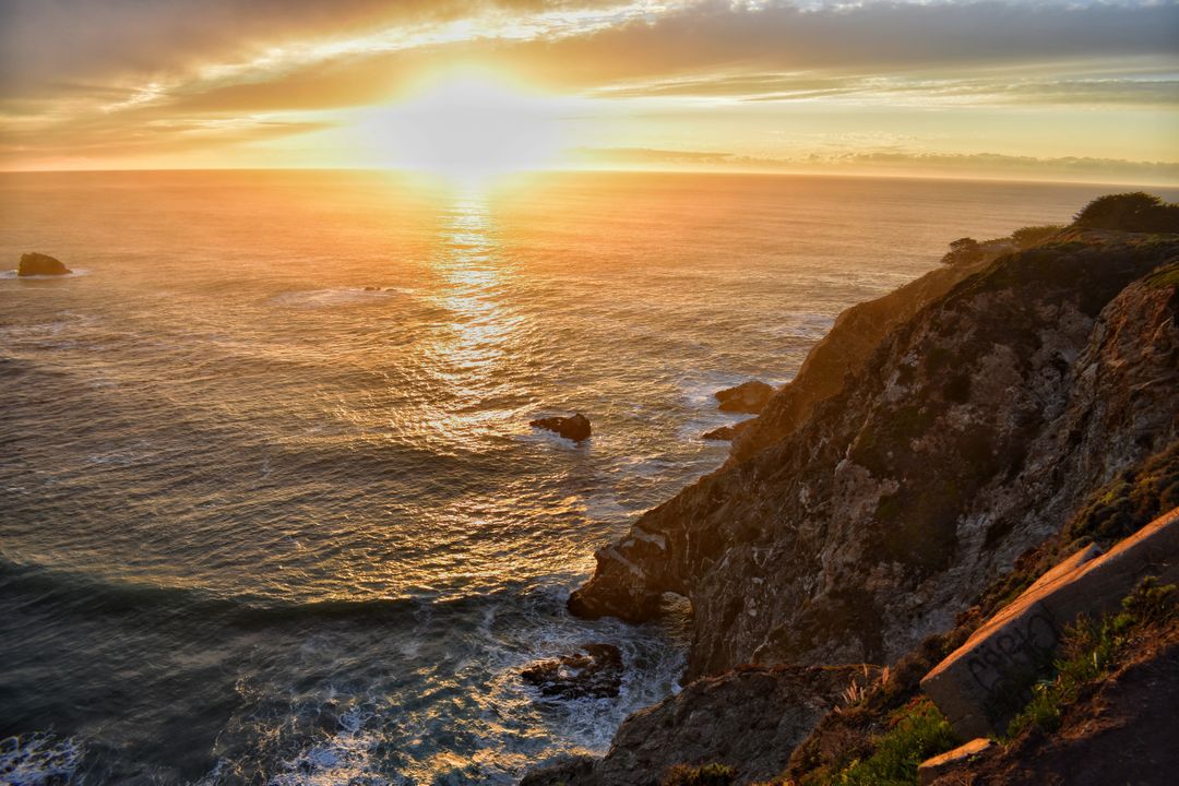 Golden Sunset Over Ocean with Rocky Cliff - Free Images, Stock Photos and Pictures on Pikwizard.com