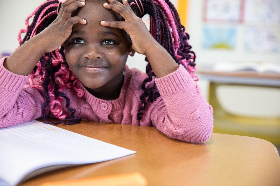 Young Girl Concentrating at School with Open Notebook