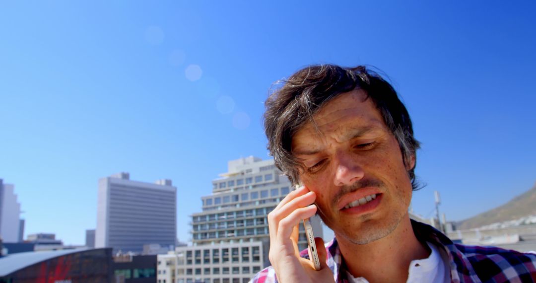 Man on Urban Rooftop Talking on Phone on a Sunny Day - Free Images, Stock Photos and Pictures on Pikwizard.com