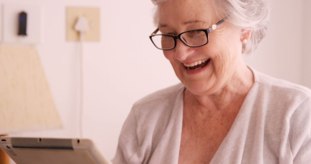 Elderly Woman Smiling While Using Tablet at Home - Free Images, Stock Photos and Pictures on Pikwizard.com