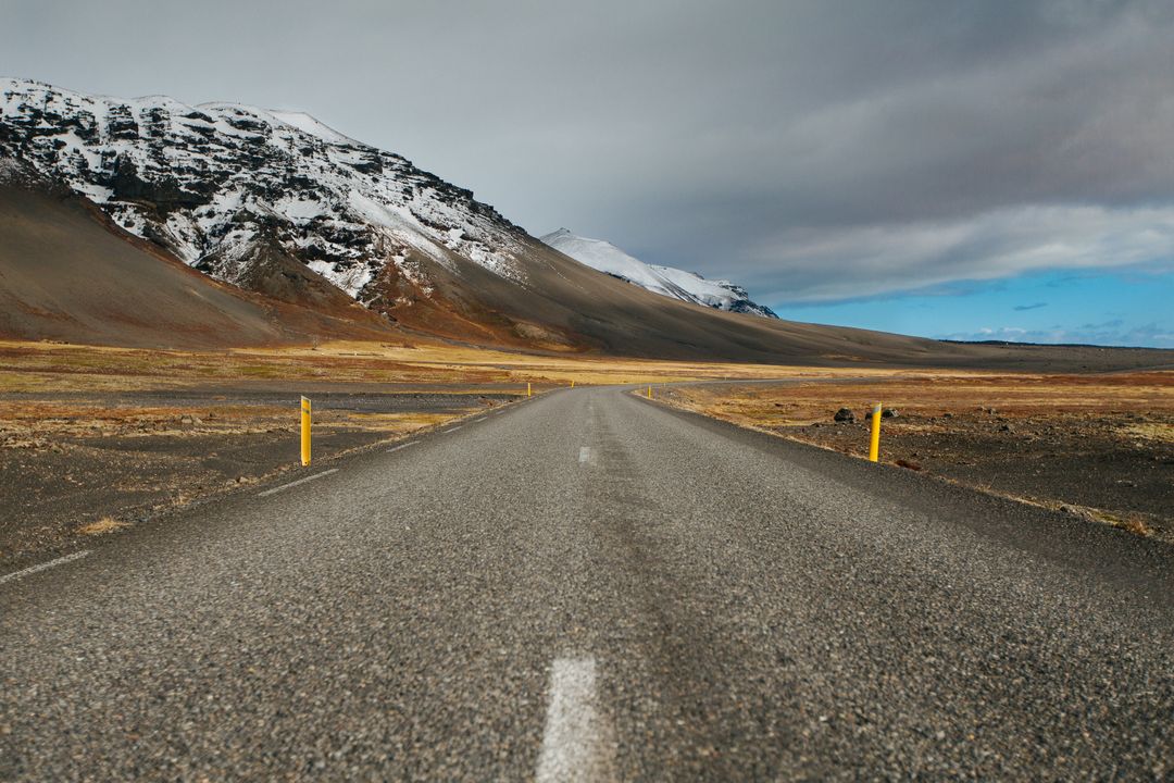 Empty Road Leading Towards Snow-Capped Mountains Under Cloudy Sky - Free Images, Stock Photos and Pictures on Pikwizard.com