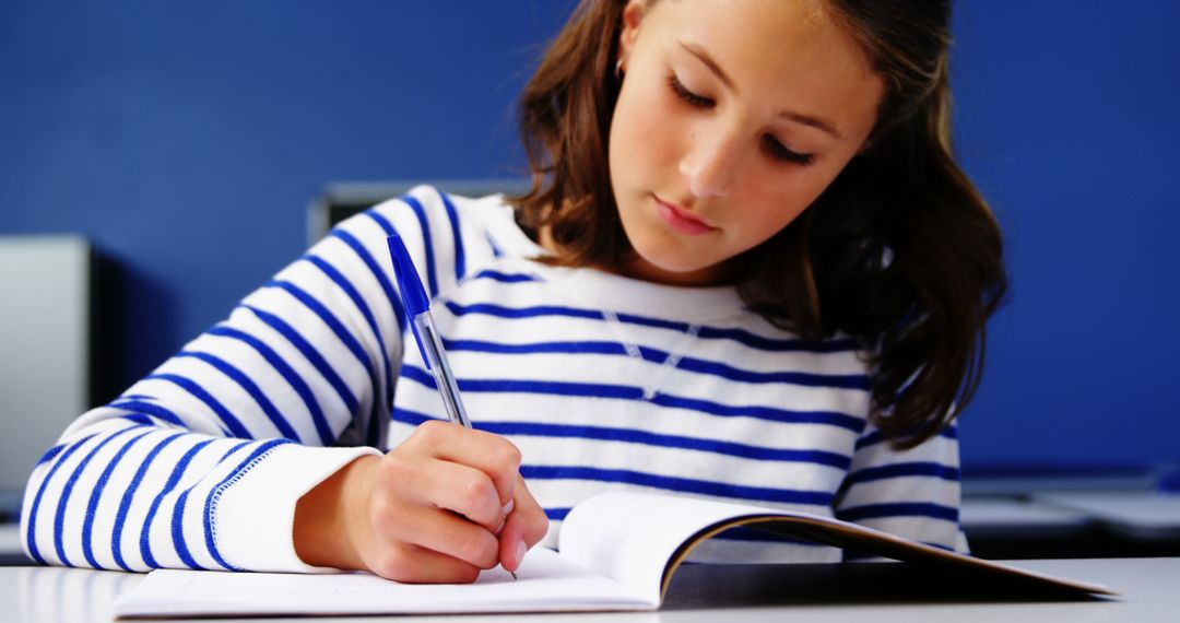 Focused Schoolgirl Writing in Notebook - Free Images, Stock Photos and Pictures on Pikwizard.com