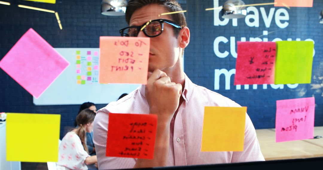 Man Brainstorming With Sticky Notes On Glass Wall In Office - Free Images, Stock Photos and Pictures on Pikwizard.com