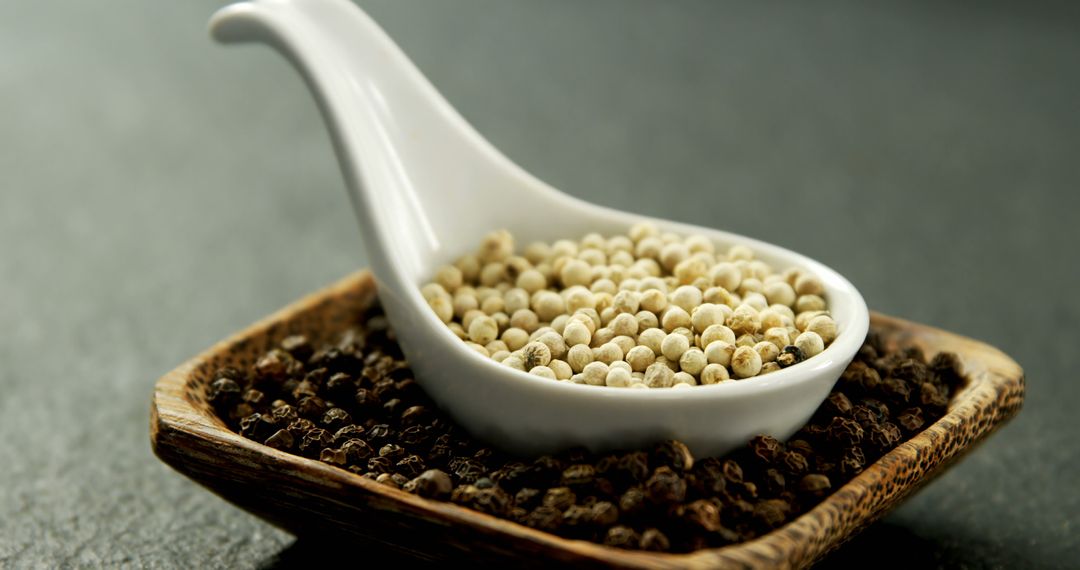 Contrasting Peppercorns in Ceramic Spoon and Wooden Dish - Free Images, Stock Photos and Pictures on Pikwizard.com