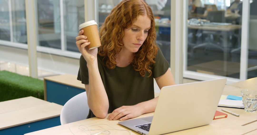 Focused Woman Working on Laptop in Modern Office with Coffee - Free Images, Stock Photos and Pictures on Pikwizard.com