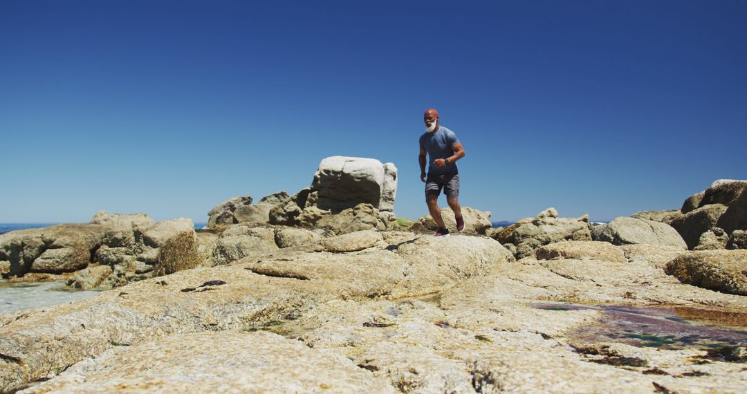 Man Hiking on Rocky Coastal Shoreline Under Clear Blue Sky - Free Images, Stock Photos and Pictures on Pikwizard.com