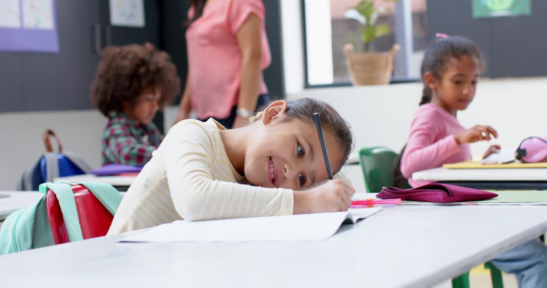 Young Student Smiling While Writing at Classroom Desk