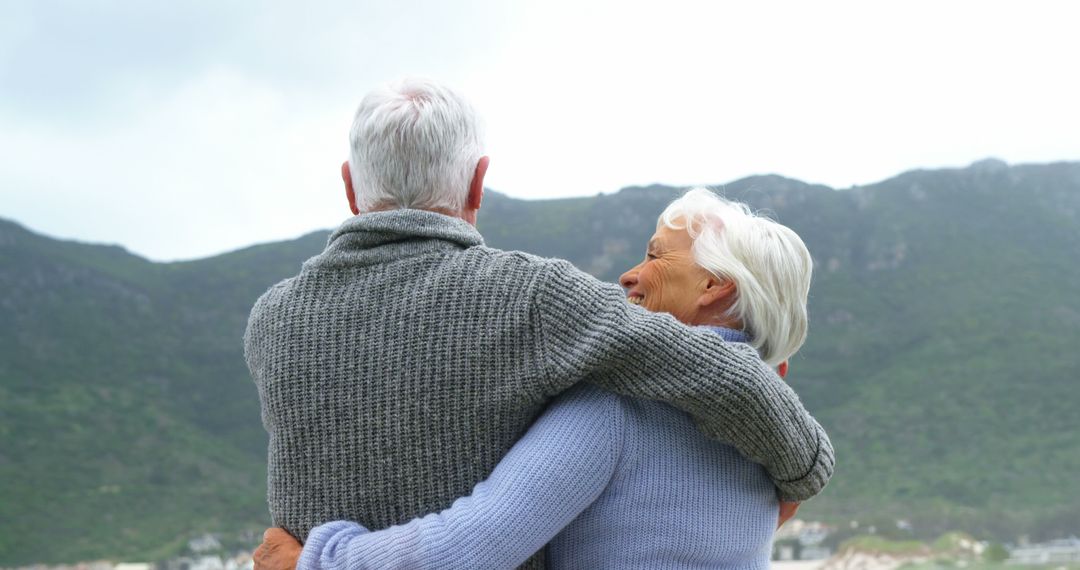 Happy Senior Couple Embracing Outdoors Looking at Mountain View - Free Images, Stock Photos and Pictures on Pikwizard.com